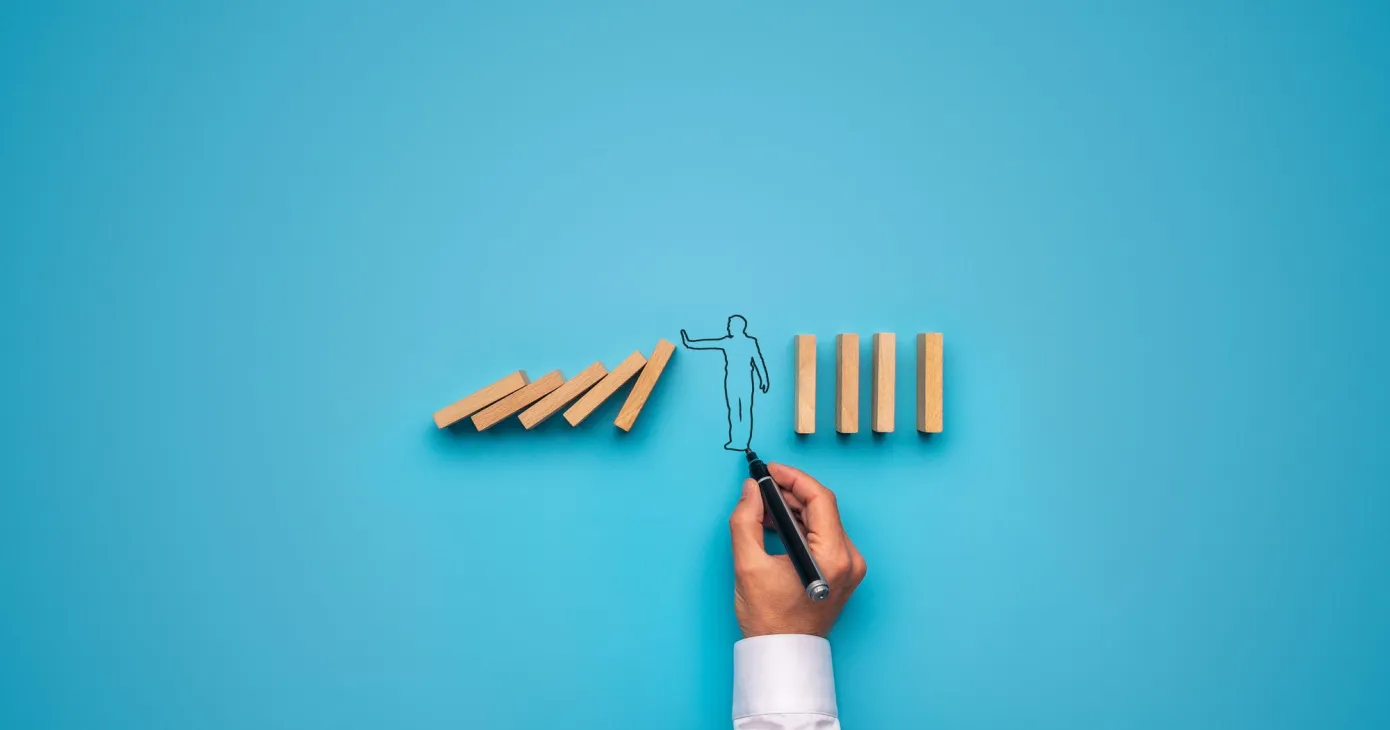 Main interrompant la chute d'une rangée de dominos