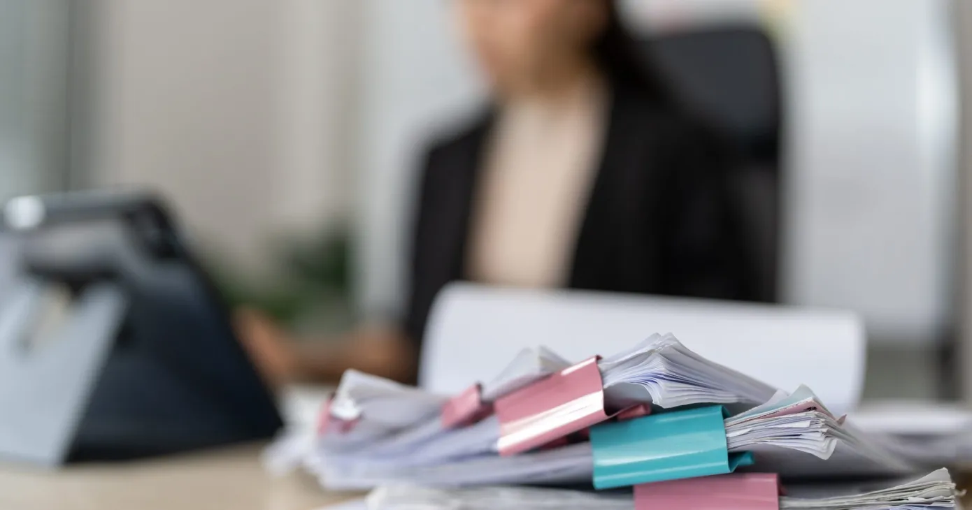 Avocate à son bureau derrière une pile de dossiers annotés