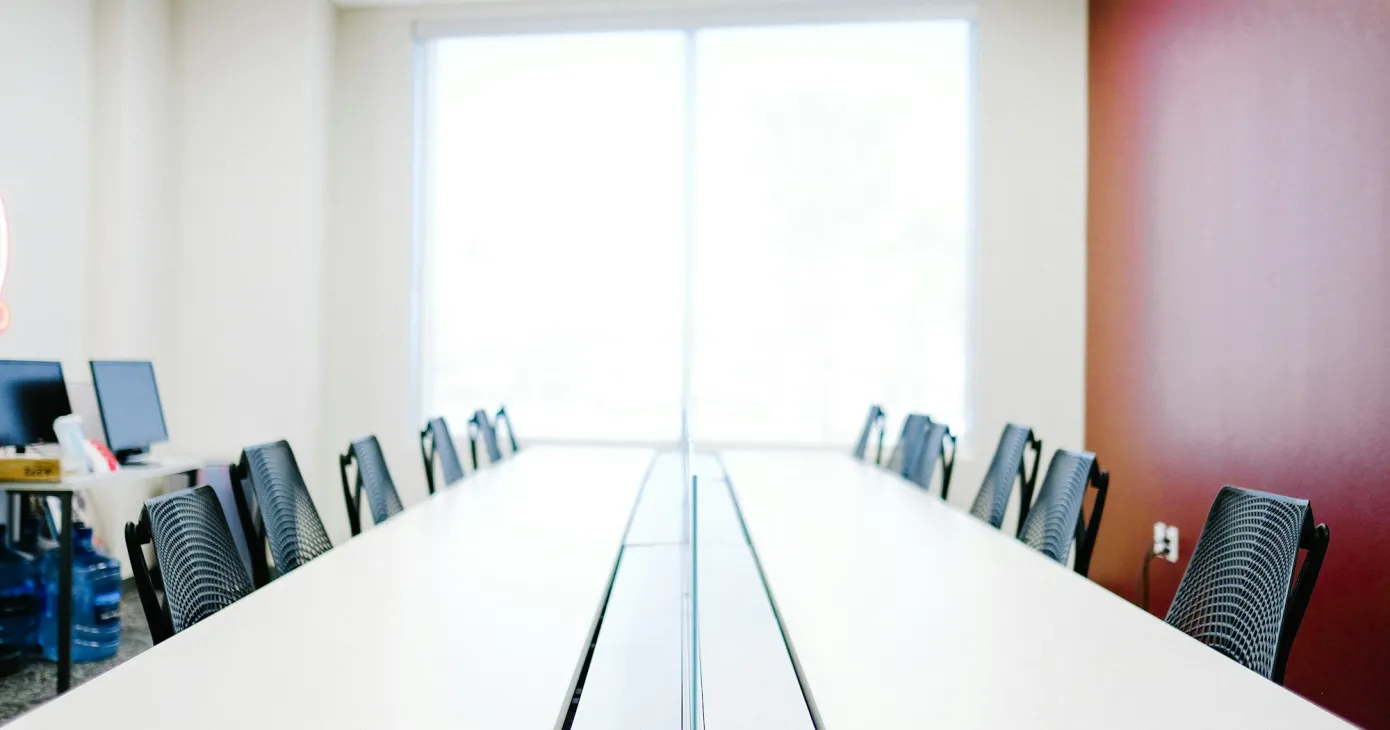 Longue table de conseil bordée de chaises, salle vide
