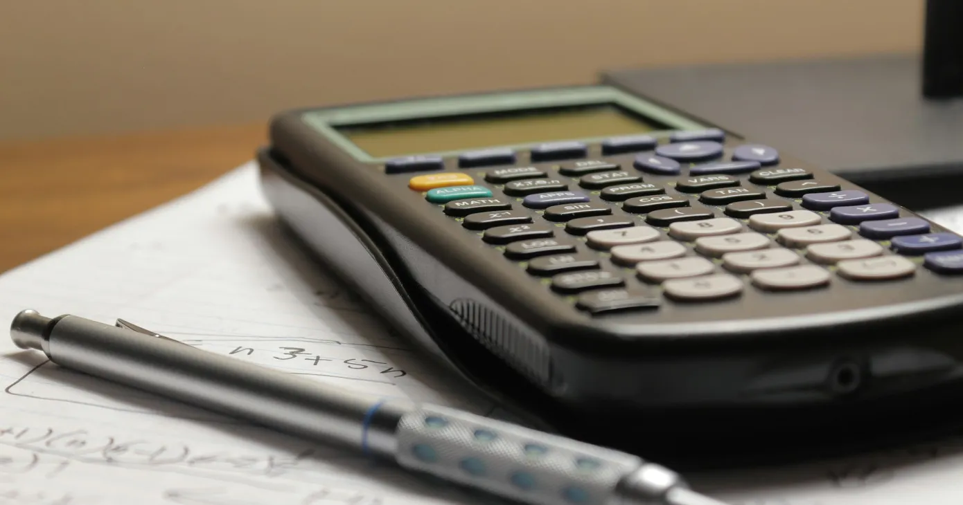 Calculatrice et stylo posés sur une page manuscrite