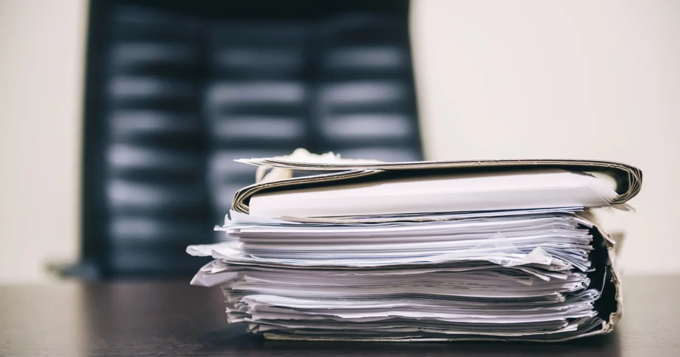 Pile de dossiers fermés posés sur un bureau