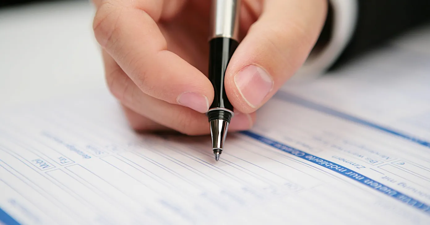 Main remplissant un formulaire au stylo