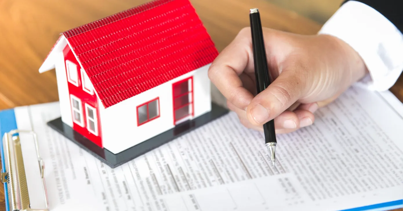 Maison miniature posée sur un contrat signé